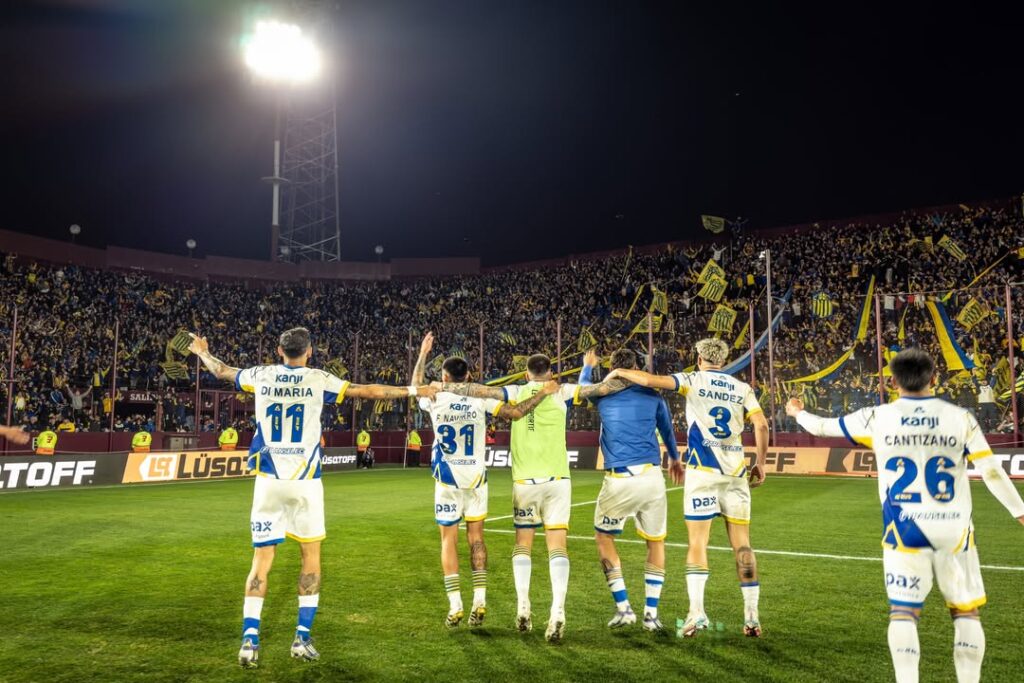 Equipe do Rosario Central comemorando com a torcida após jogo contra o Lanús, fora de casa.