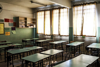 Sala de aula vazia com mesas verdes