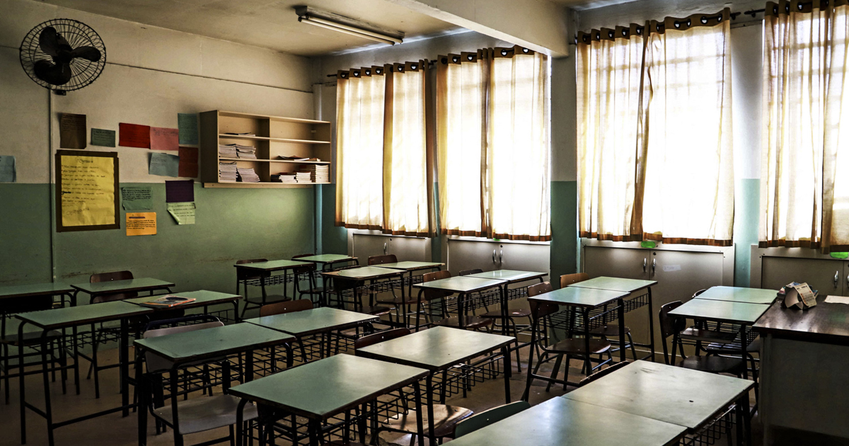 Sala de aula vazia com mesas verdes