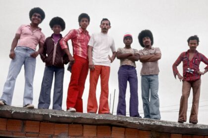 Fotografia de moradores do Aglomerado da Serra, em Belo Horizonte, posando em evento comunitário, parte da exposição 'Retratistas do Morro' no MAR.