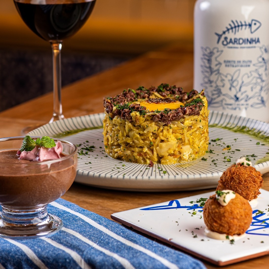 A Sardinha Taberna Portuguesa traz os sabores tradicionais de Portugal ao festival Sabores com Vista, no Botafogo Praia Shopping, com um menu completo por R$89. A experiência começa com bolinhos de alheira, segue com o clássico Bacalhau à Brás e termina com o irresistível pastel de nata, símbolo da doçaria lusitana. Com receitas cheias de história e afeto, a Sardinha Taberna Portuguesa oferece uma viagem gastronômica que celebra o sabor, a tradição e o encanto da cozinha portuguesa.