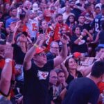 Torcedores lotam o Armazém 3 do Pier Mauá durante o Super Bowl LX Experience, no Rio de Janeiro, vibrando com a transmissão ao vivo da NFL, muitos vestidos com camisas de franquias como Kansas City Chiefs e San Francisco 49ers, em clima de festa e celebração do futebol americano.